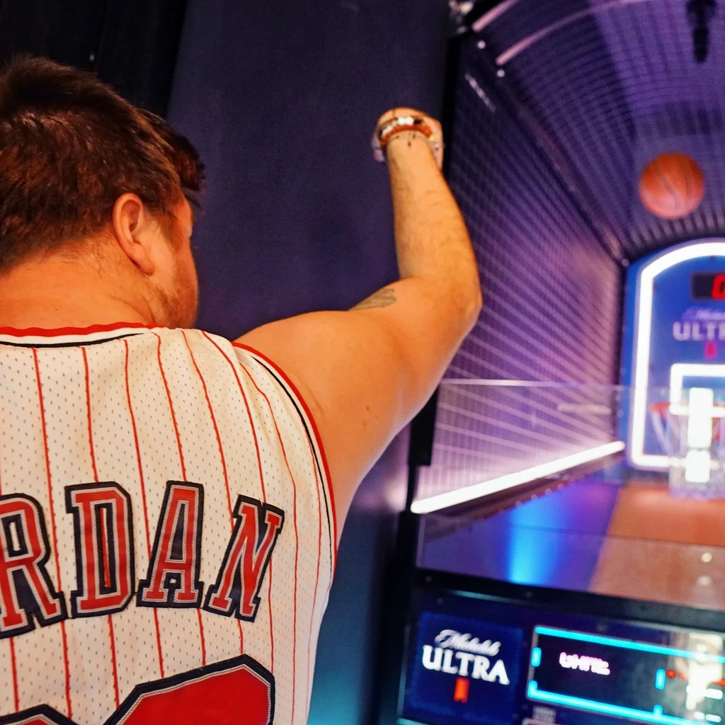 Person in Jordan jersey shooting basketball at an arcade game.
