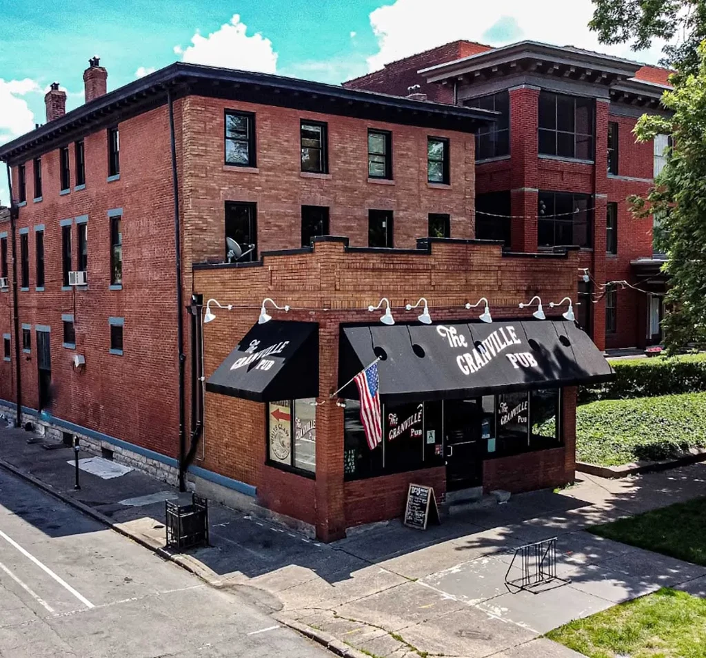 Two-story red brick building housing The Granville Pub on a sunny day.