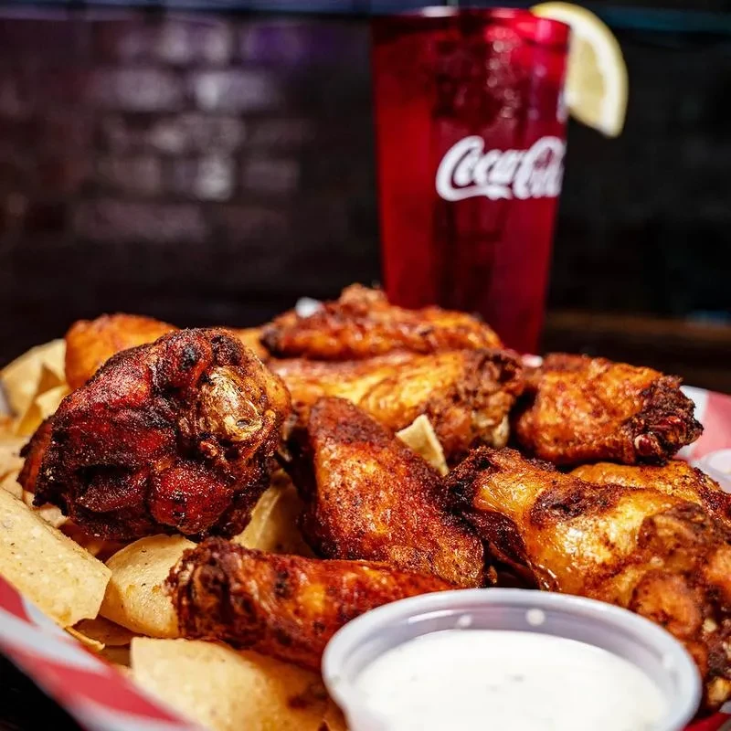 Crispy chicken wings with tortilla chips, dipping sauce, and Coca-Cola.