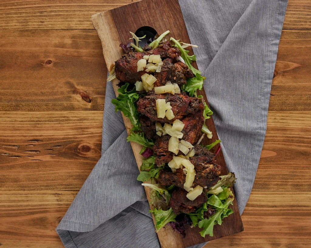 Overhead view of grilled meat, pineapple, lettuce on a wooden board.
