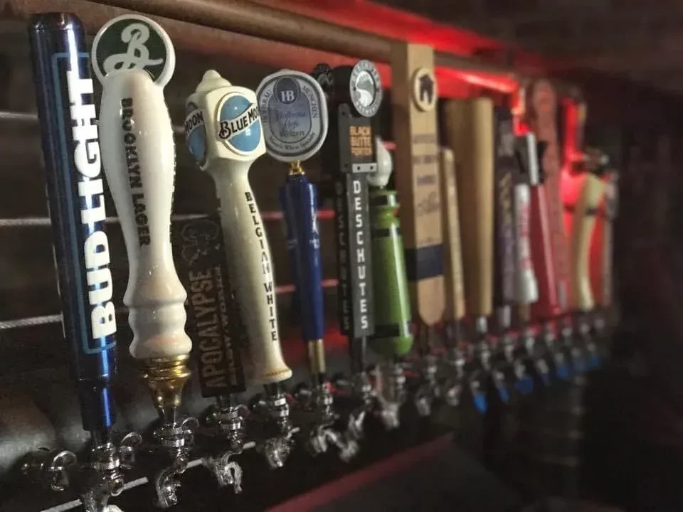 A row of beer taps with Bud Light, Blue Moon, and more.