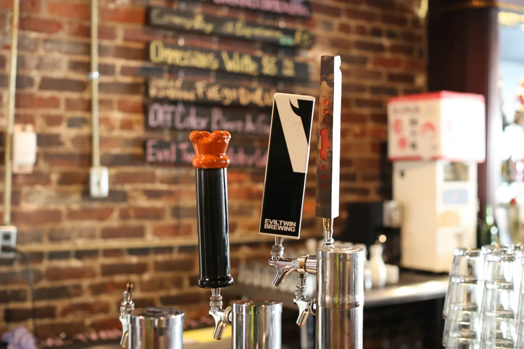 Three distinct beer taps, including Evil Twin, on a bar.