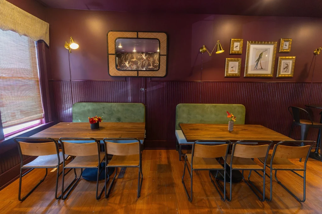 Restaurant interior with green velvet booths and plum walls.