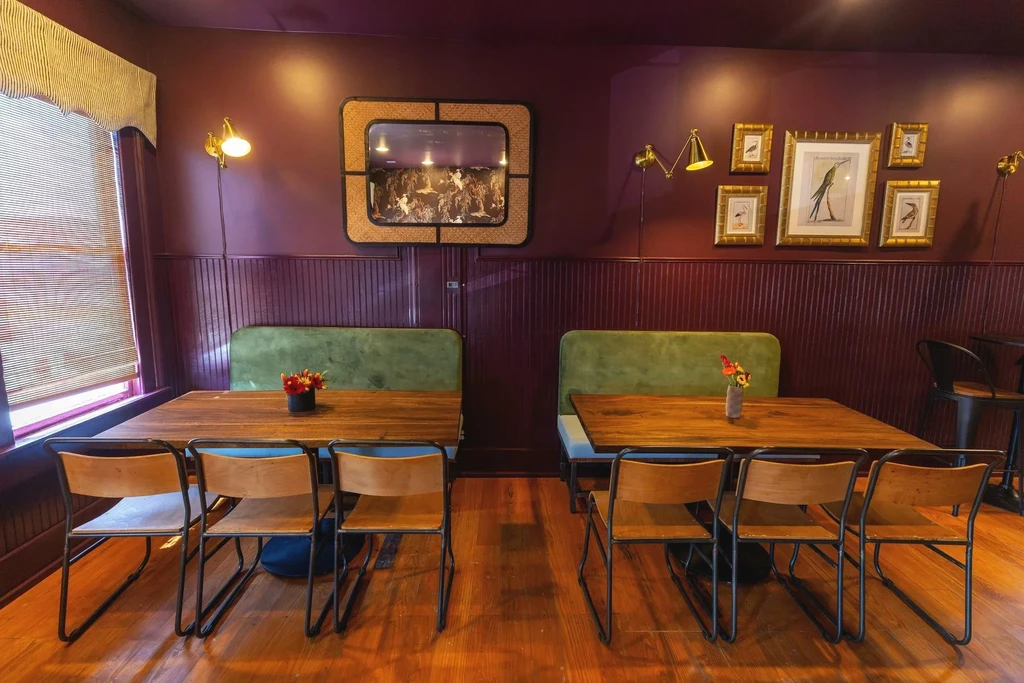 Plum-walled restaurant interior featuring olive green booths and bird gallery wall.
