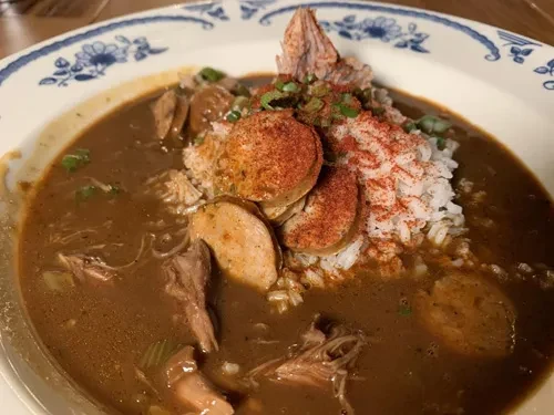 Top-down view of dark gumbo with rice, chicken, and sausage.