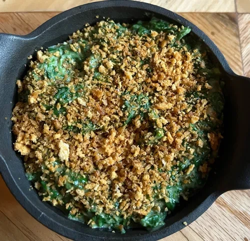 Creamed spinach with crunchy topping in a black cast-iron pan.