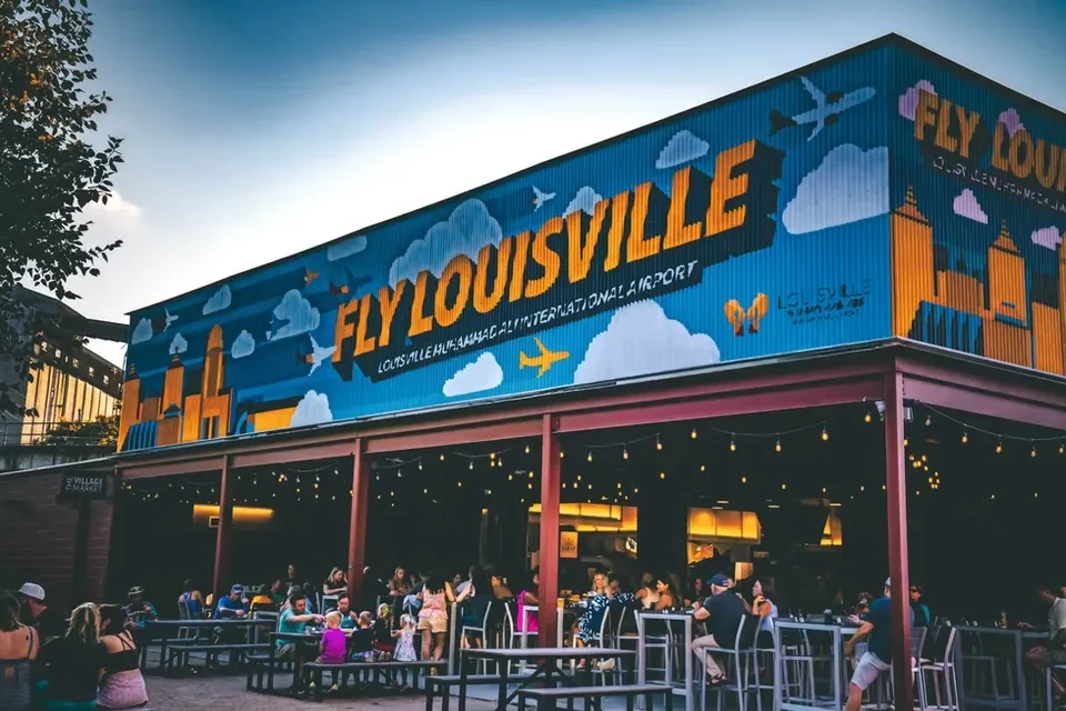 Restaurant patio with a colorful 'FLY LOUISVILLE' airport mural.