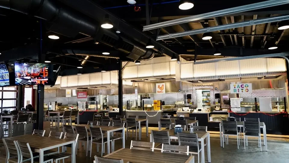 Empty modern food hall with industrial design and diverse food stalls.