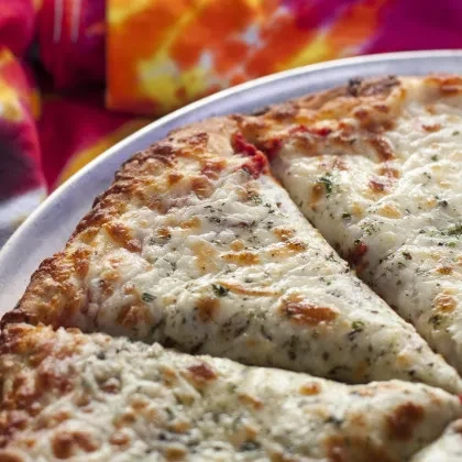 Freshly baked white cheese pizza with herbs, sliced on a metal pan.