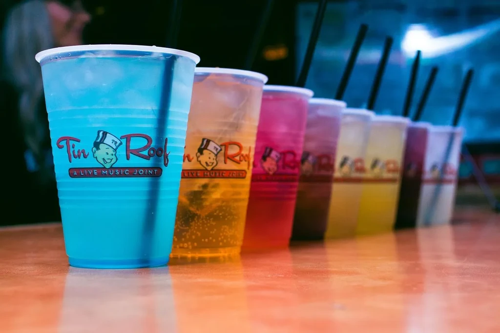 Row of colorful branded drinks in plastic cups.