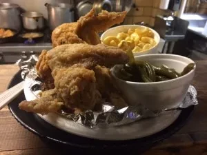 Crispy fried chicken, mac and cheese, and string beans on dark plate.