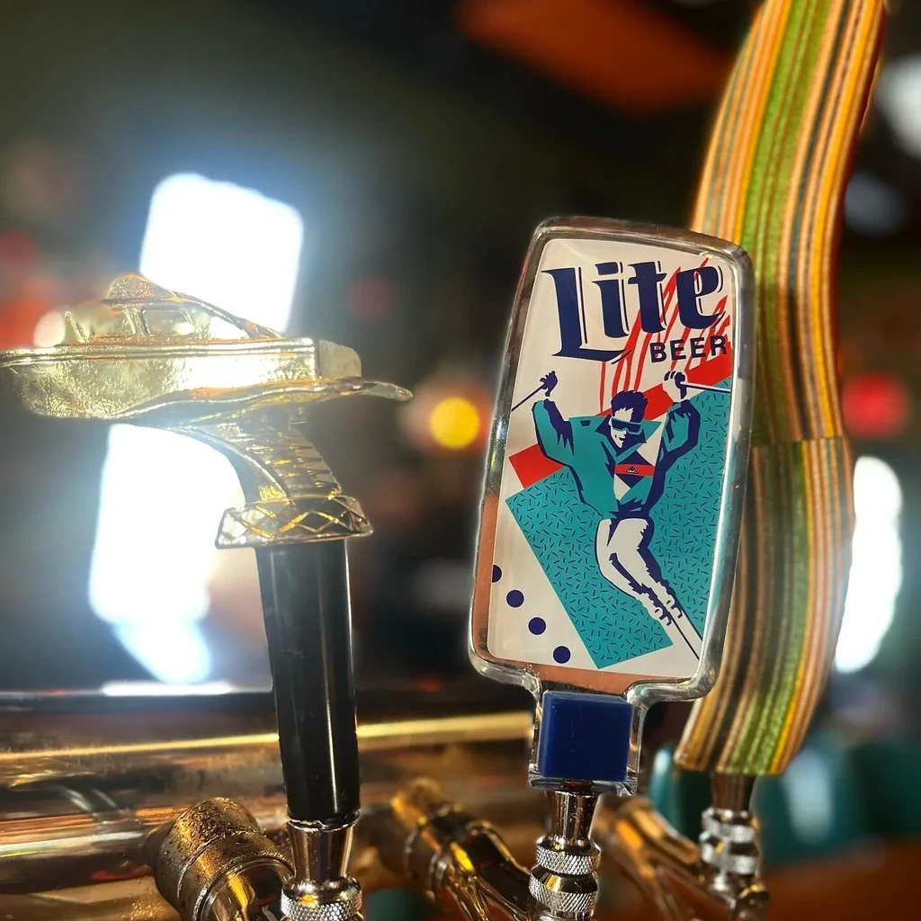 Close-up of two beer tap handles: Lite Beer skier and golden boat.