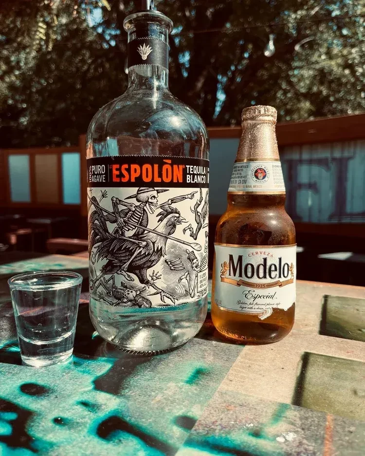 Espolón Tequila, Modelo beer, shot glass on a colorful outdoor table.