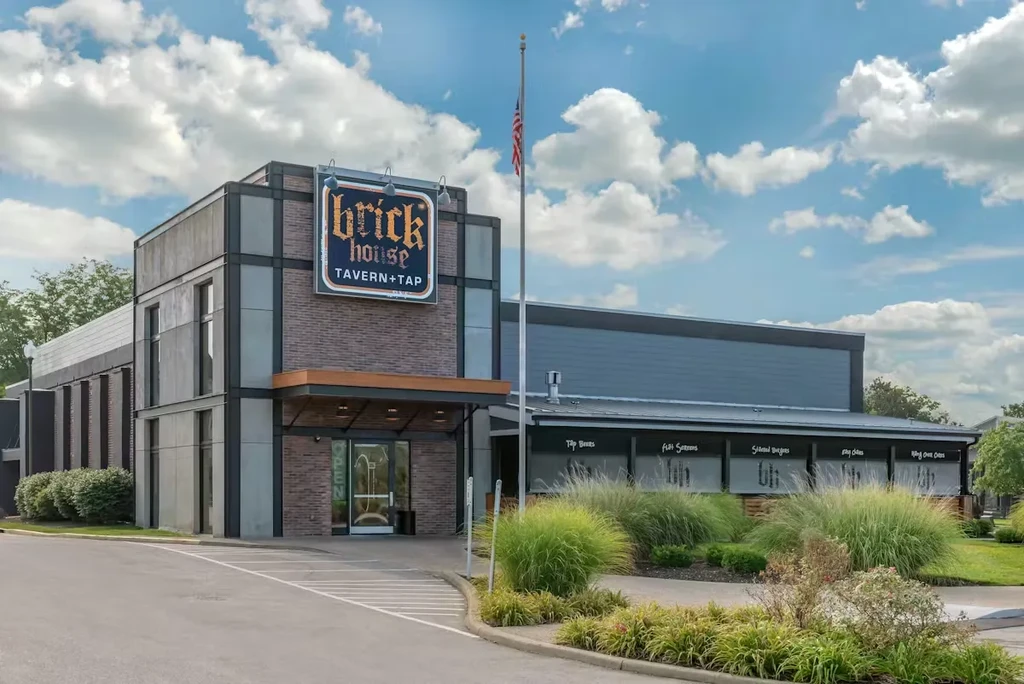 Modern Brick House Tavern + Tap exterior with flag and landscaping.