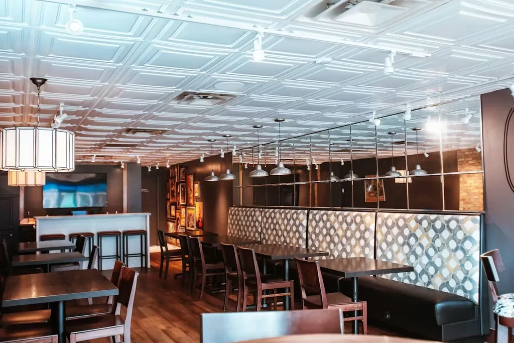 Modern restaurant interior with patterned tin ceiling and geometric booth.