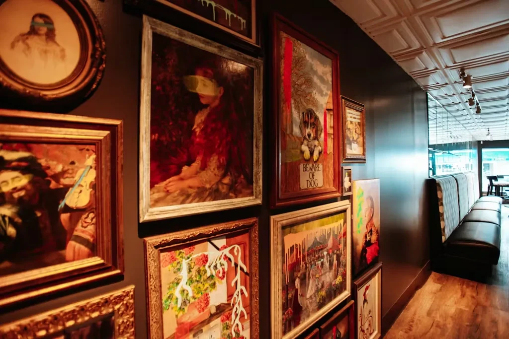 Restaurant interior with dark booths and a wall of eclectic art.