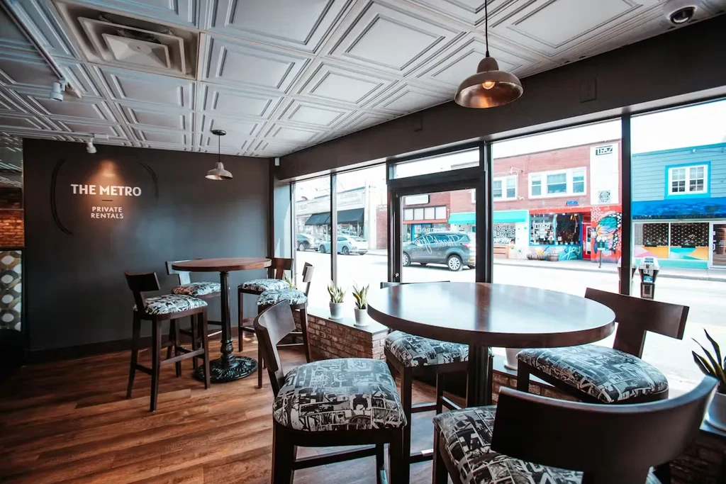 Modern cafe interior with high-top tables, brick wall, and street view.