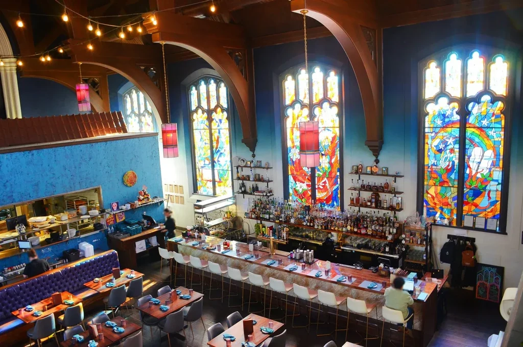 Repurposed church bar and restaurant with intricate stained-glass windows.