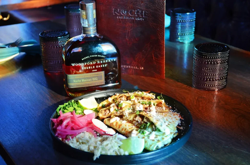 Woodford Reserve bourbon bottle, Noche menu, and garnished tacos.