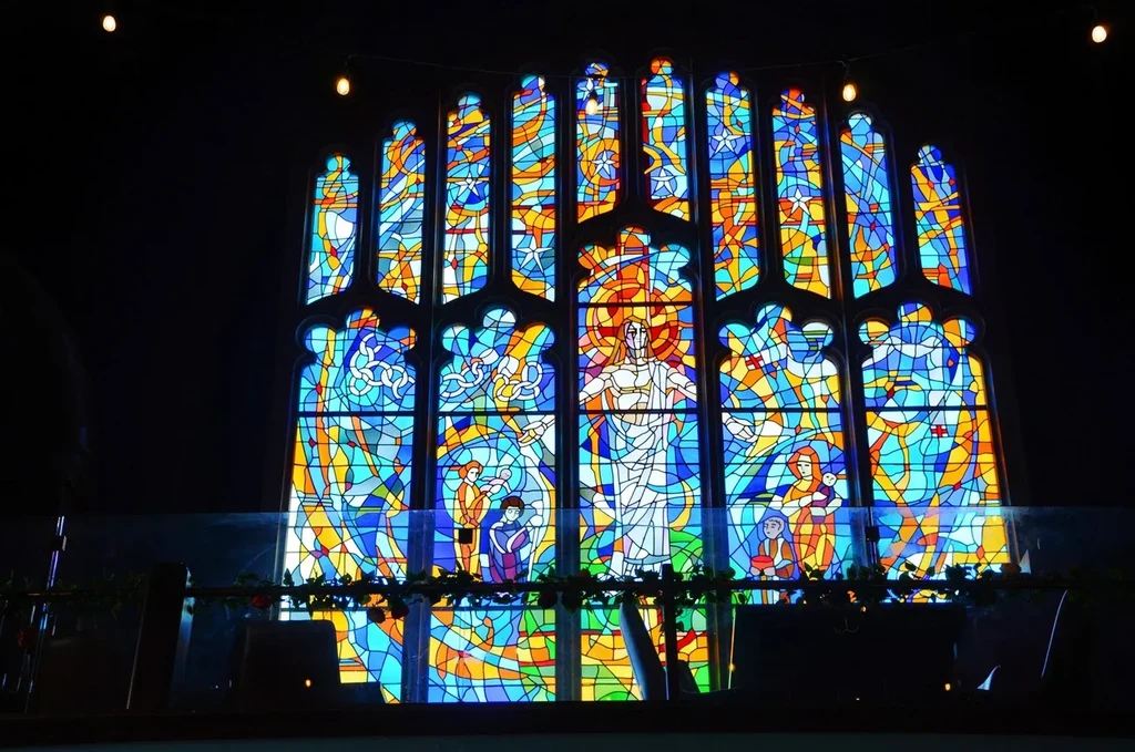 Ornate gothic stained glass window with religious figures and bright colors.