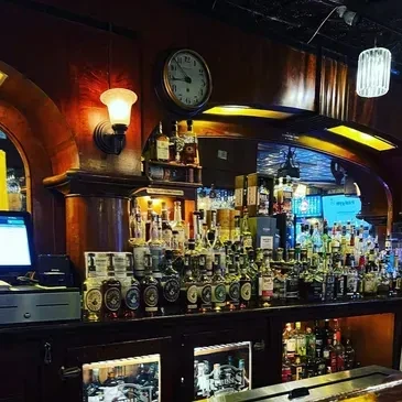 Classic bar interior, well-stocked counter, large mirror, Roman numeral clock.