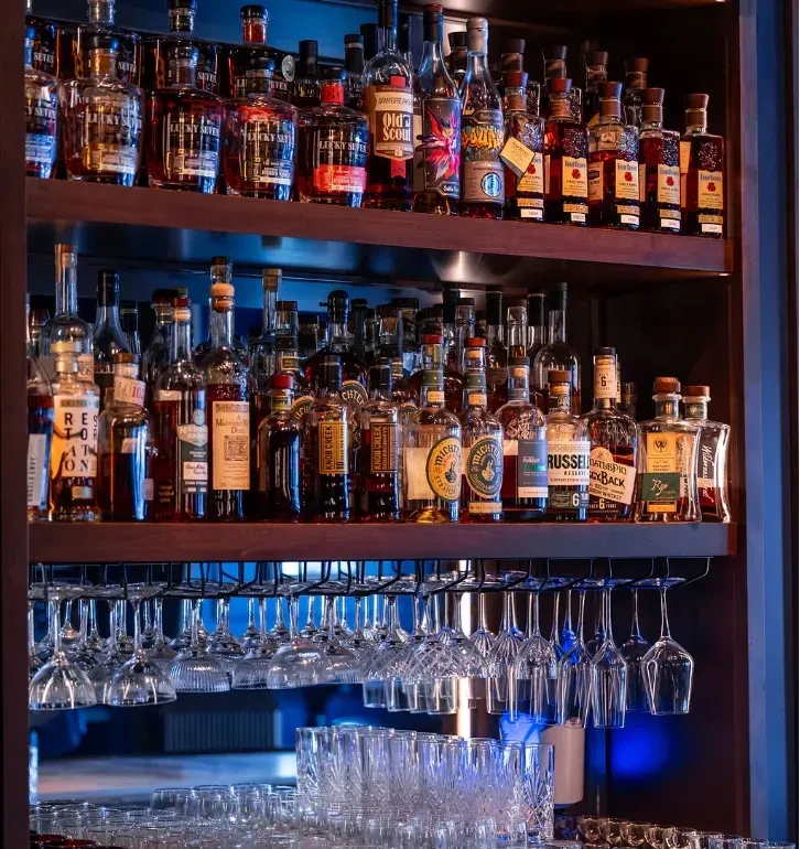 A well-stocked bar display with various whiskey bottles and clean glassware.