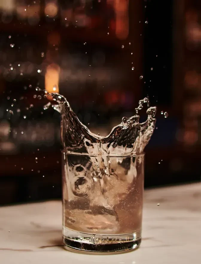 Clear glass with a dynamic water splash and airborne droplets.