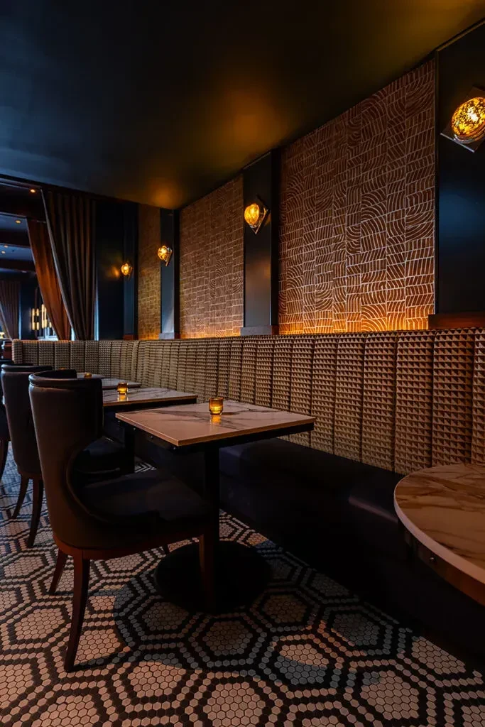 Warmly lit, upscale restaurant interior with patterned walls and mosaic floor.