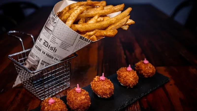Crispy fries in newspaper cone, four fried appetizers with pink sauce.