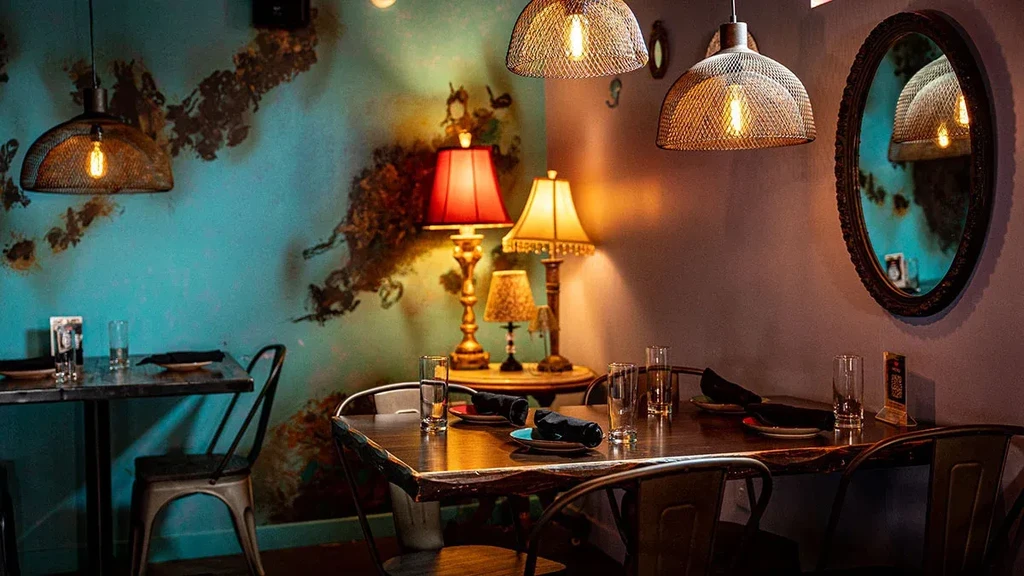 Empty restaurant interior showing two set tables and decorative lighting.