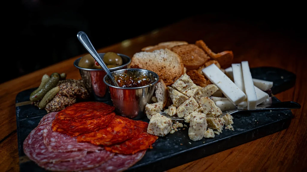 Charcuterie and cheese board with meats, cheeses, olives, and crackers.