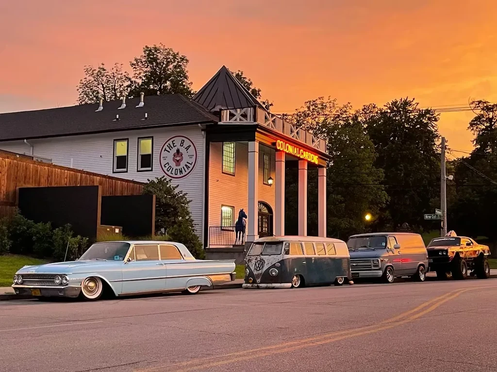 Colonial Gardens restaurant at sunset, with four classic and custom vehicles.