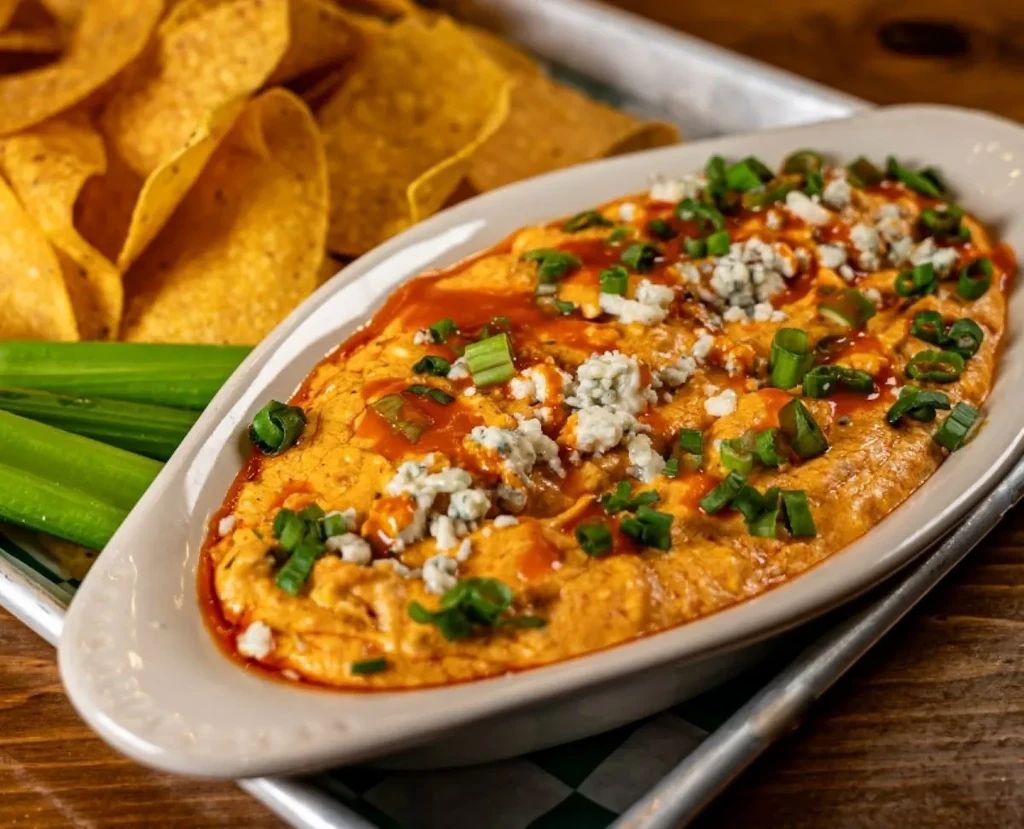 Buffalo chicken dip with blue cheese, hot sauce, green onions, celery, chips.