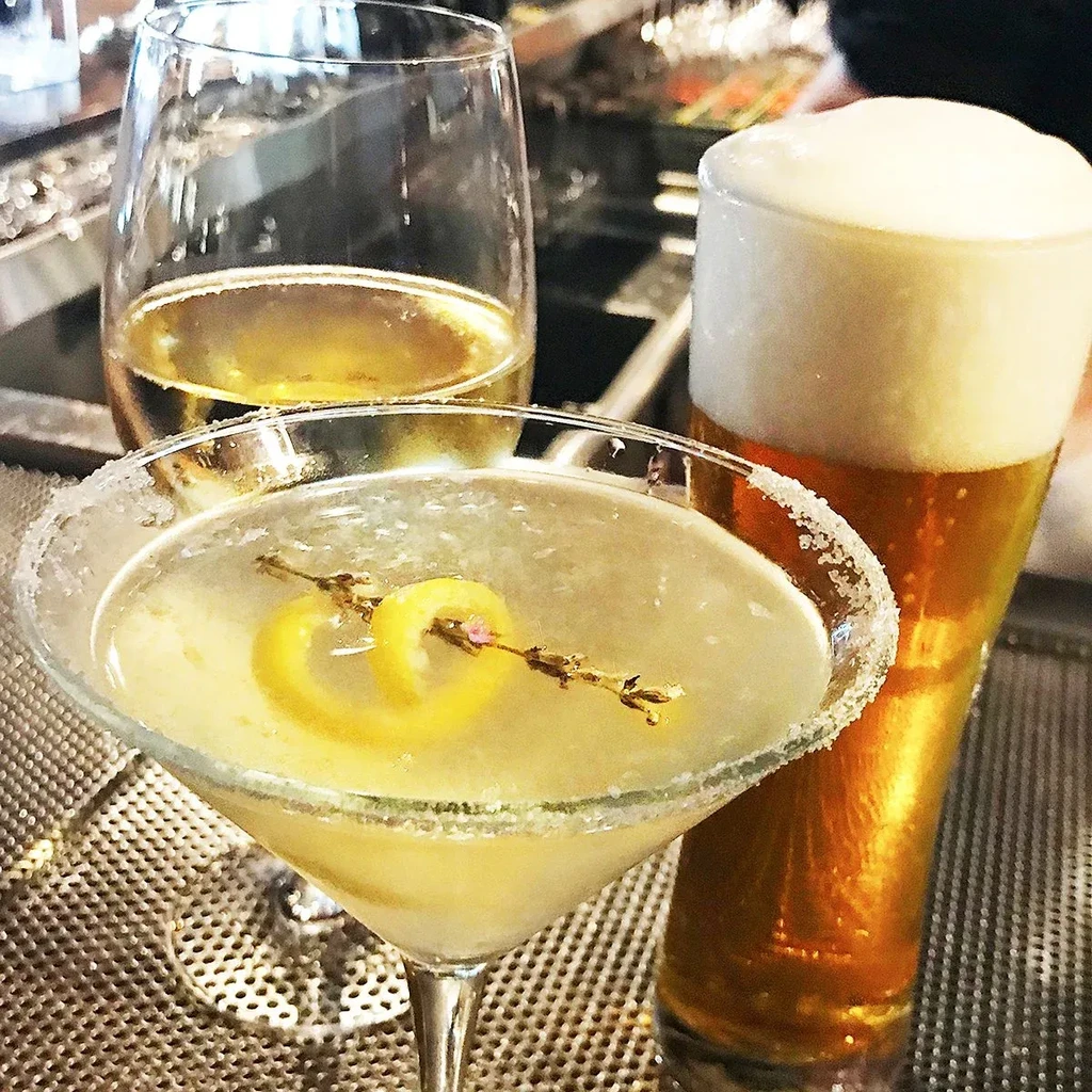Martini, wine, and beer on a metallic bar surface.