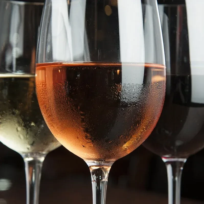 Three wine glasses: chilled rosé, white, and red, with condensation.