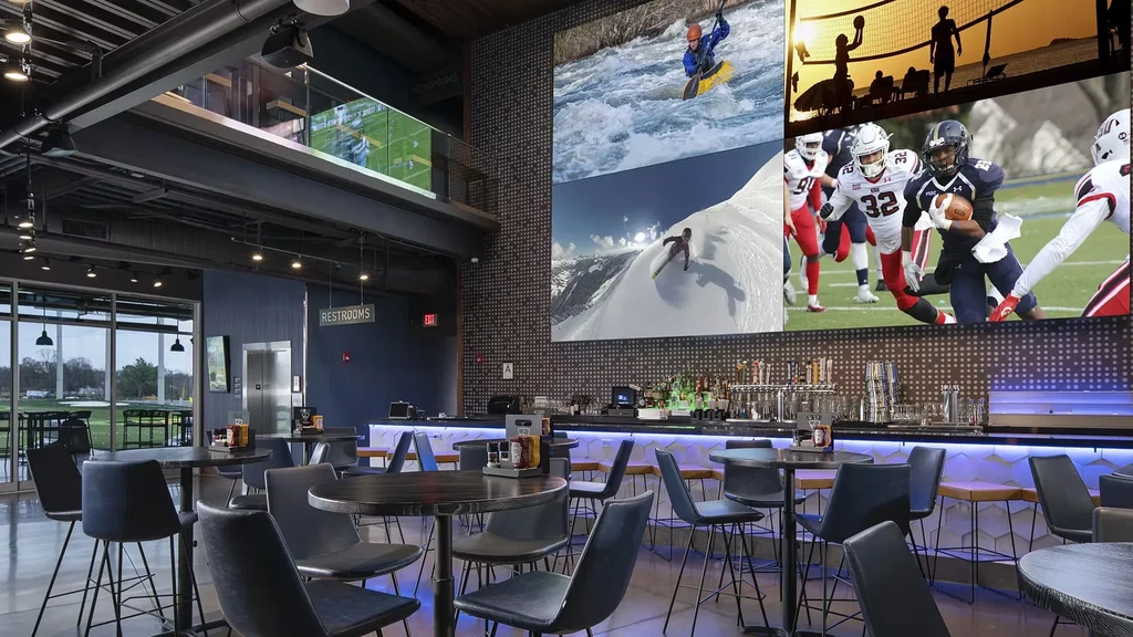 Modern sports bar with large video wall showing diverse sports.
