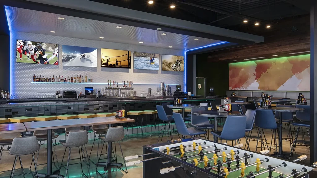 Modern sports bar interior with large bar, multiple TVs, and seating.