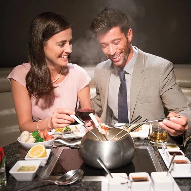 Happy couple smiling, enjoying a fondue dinner at a restaurant.