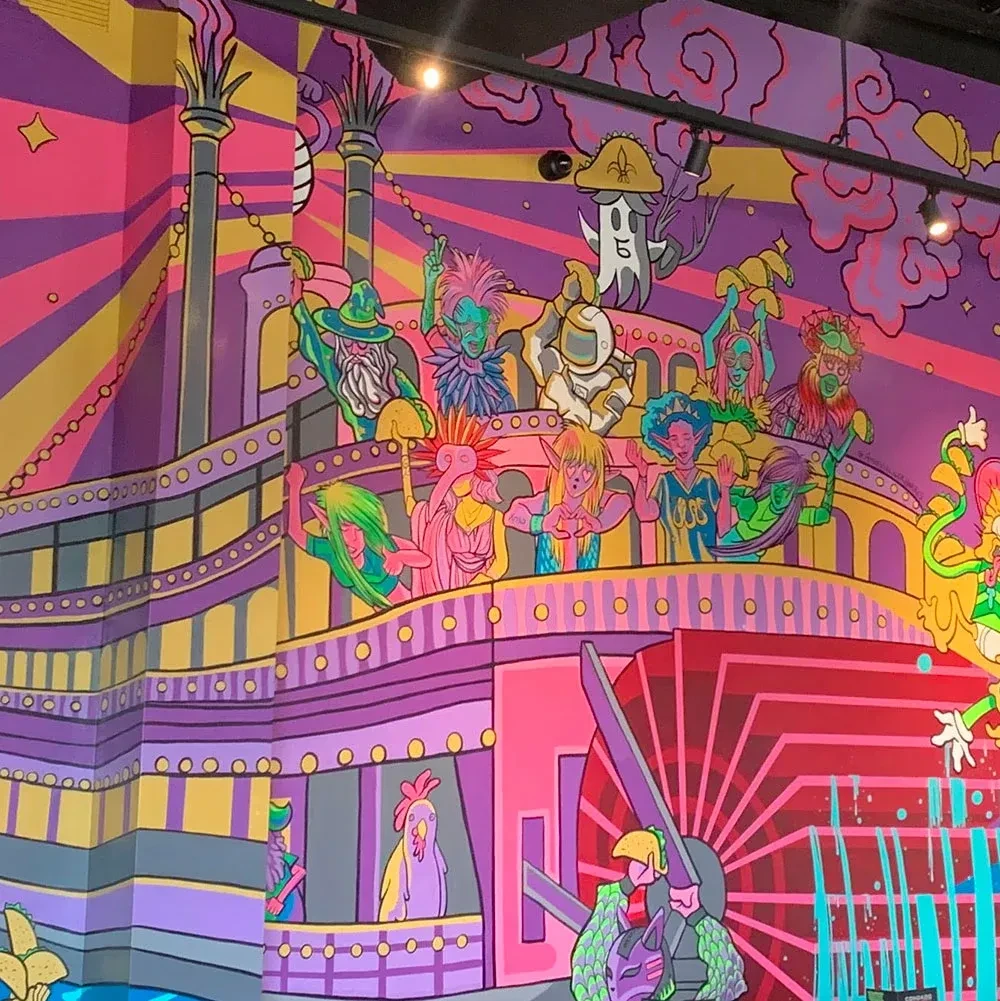 Vibrant, stylized mural of fantastical steamboat with cartoon characters.