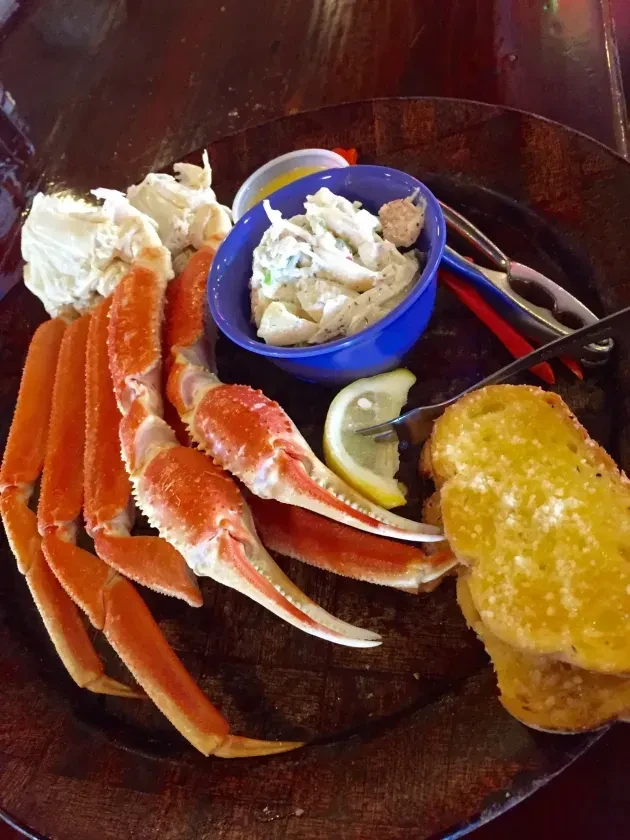 Cooked crab legs, garlic bread, salad, melted butter, and lemon.