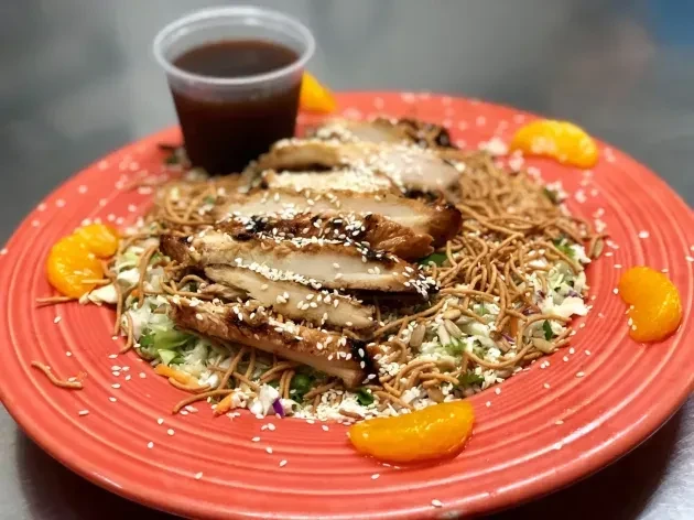 Grilled chicken salad with sesame, crispy noodles, mandarin, and sauce.