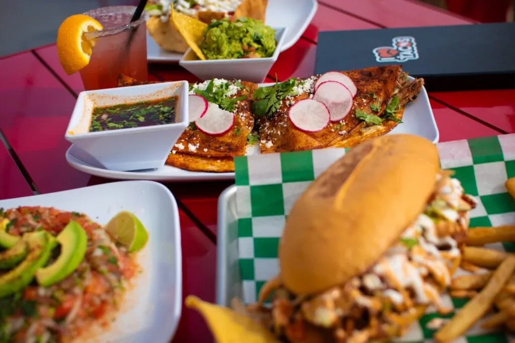 Sharp focus on folded savory dishes, with a blurry sandwich and ceviche.