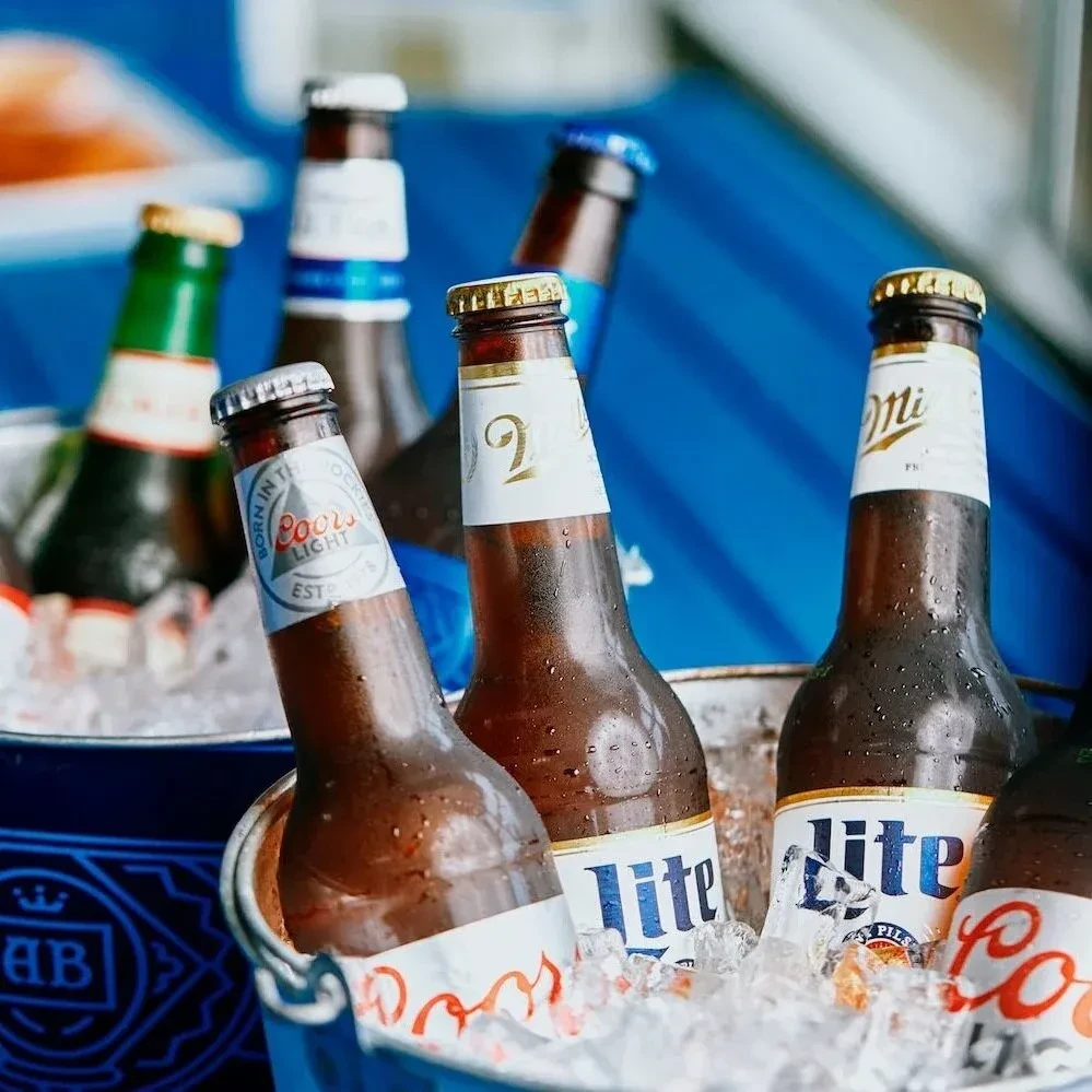 Cold Coors Light and Miller Lite bottles chilling in ice buckets.