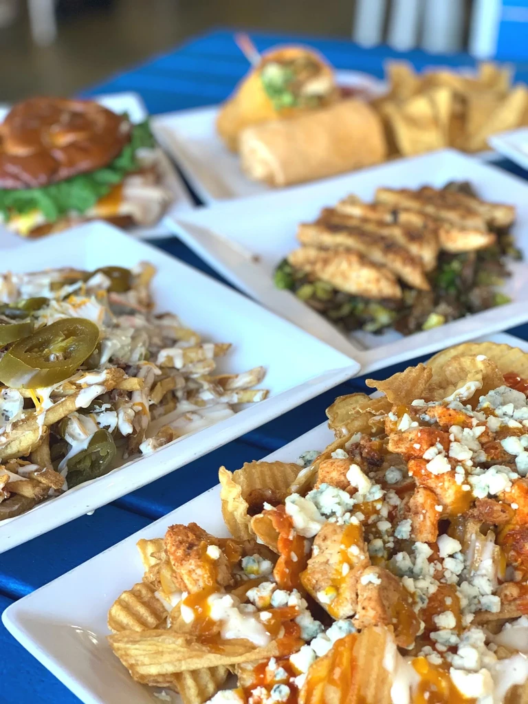 Overhead shot of waffle fries with buffalo chicken and multiple dishes.