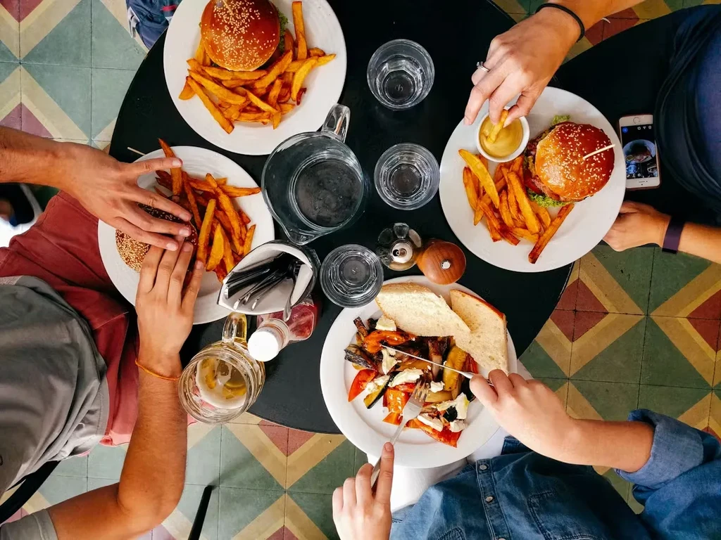Overhead: Burgers, fries, vegetables, and drinks on a table.