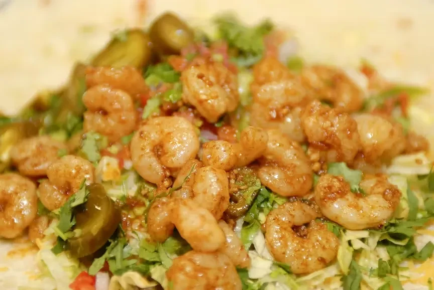 Seasoned shrimp dish with lettuce, tomatoes, cilantro, and pickled jalapeños.