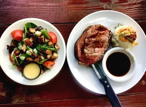 Overhead: Roasted meat, mashed potatoes, and salad on a wooden table.