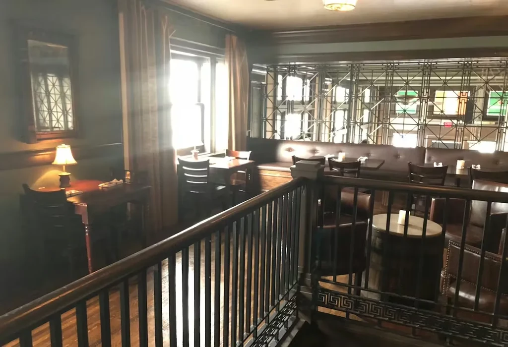 Empty restaurant interior with leather seating, dark wood, and metal partition.