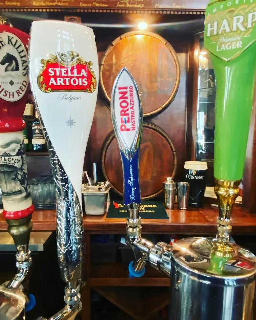 Close-up of Stella Artois, Peroni, Harp beer taps on a bar.