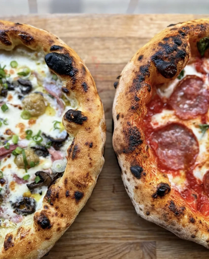 Two Neapolitan pizzas, one white and one pepperoni, on wood.